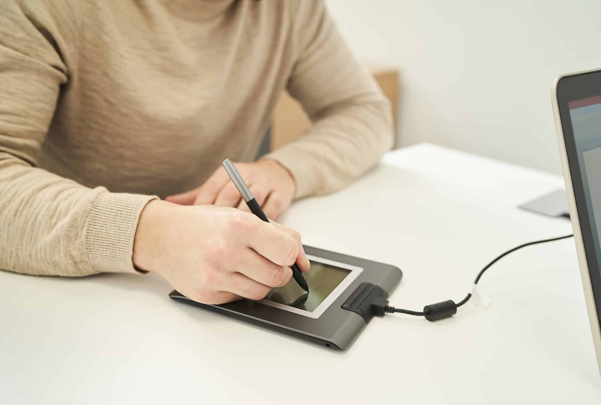 a man signing on a digital tablet