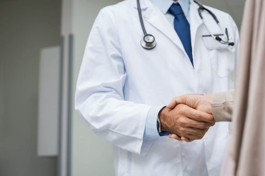 Dokter die een patiënt zijn hand schudt - Wat doet een keurdokter? - Rijbewijsdokter