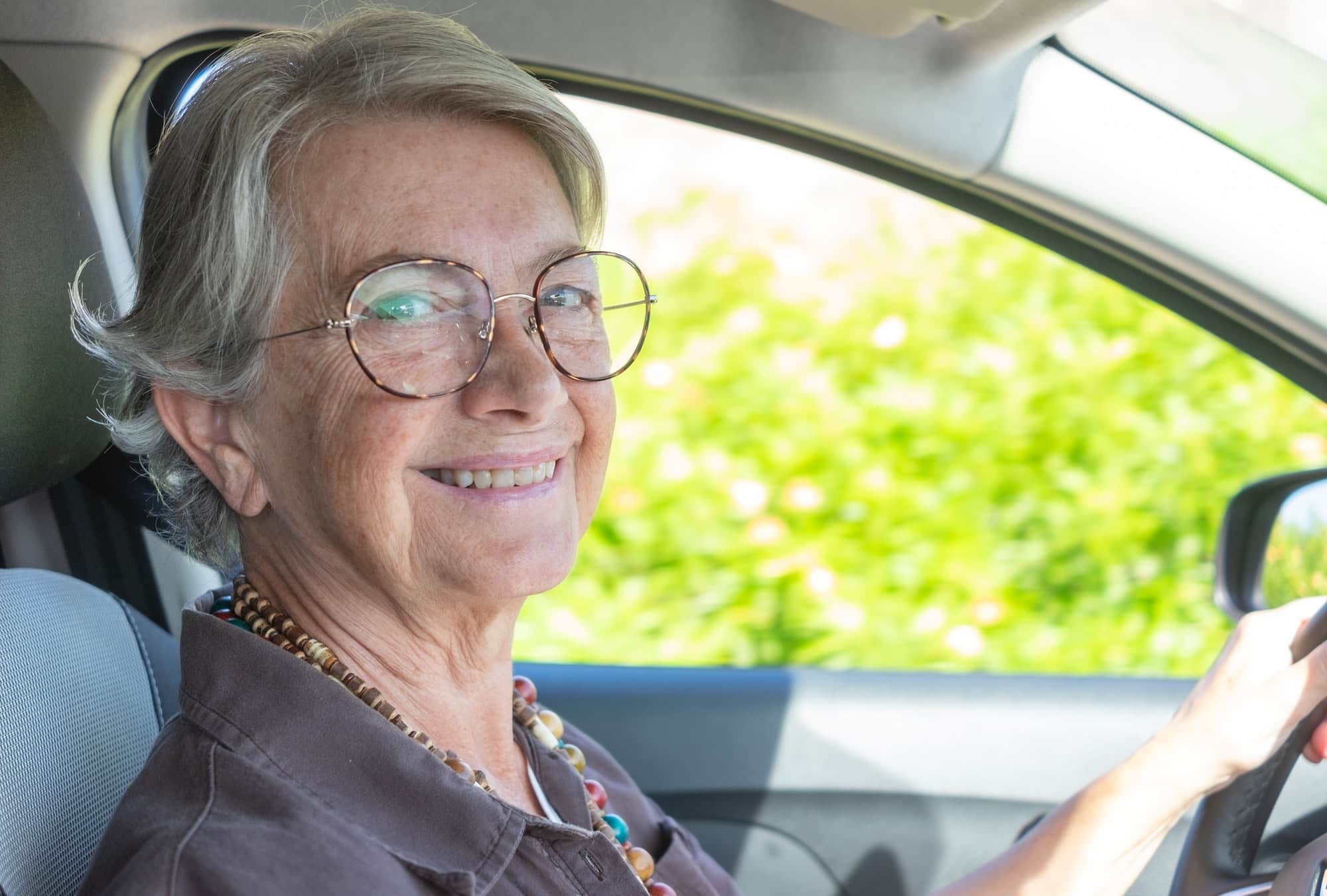 Senior caucasian woman driving the car, elderly lady enjoying drive and travel