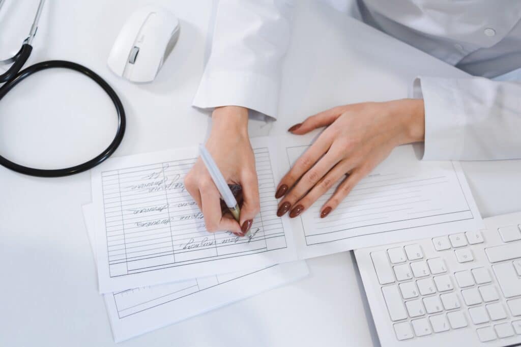 Close up view of female doctor hands filling paperwork