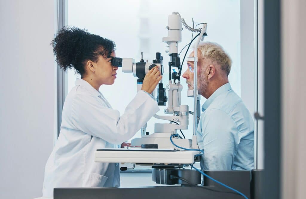 Visie en oogtest met een vrouwelijke arts of optometrist die de ogen van een mannelijke patiënt test | Oogarts rijbewijskeuring | Rijbewijsdokter