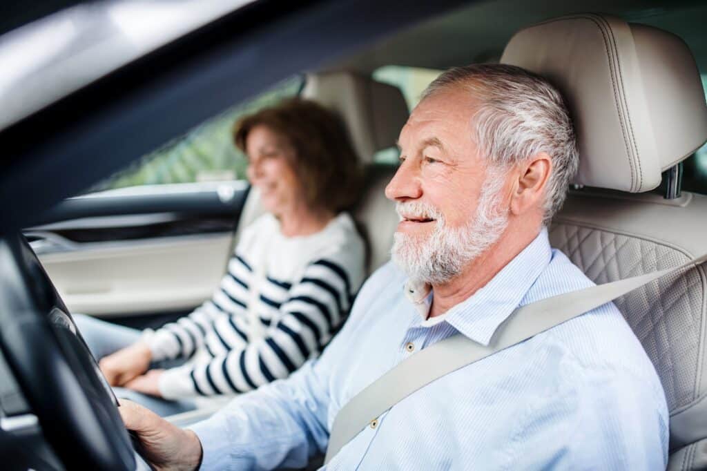 Gelukkig ouder echtpaar zittend in de auto, rijdend | op welke leeftijd moet je gekeurd worden voor je rijbewijs | Rijbewijsdokter