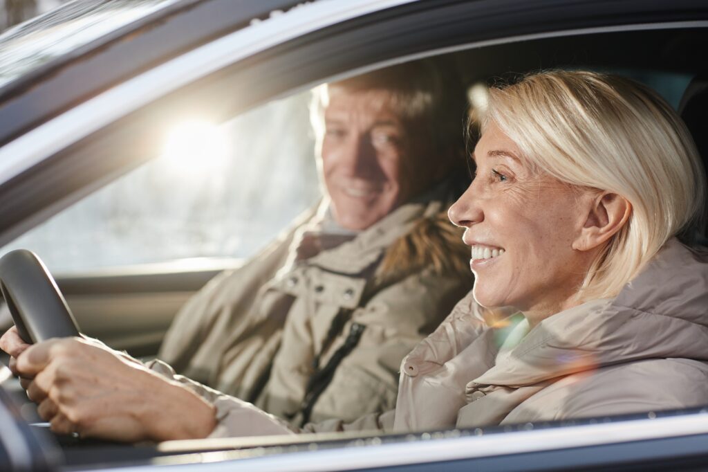 Senior koppel die in auto rijden met zon door het zijraam | rijbewijs keuren | Rijbewijsdokter